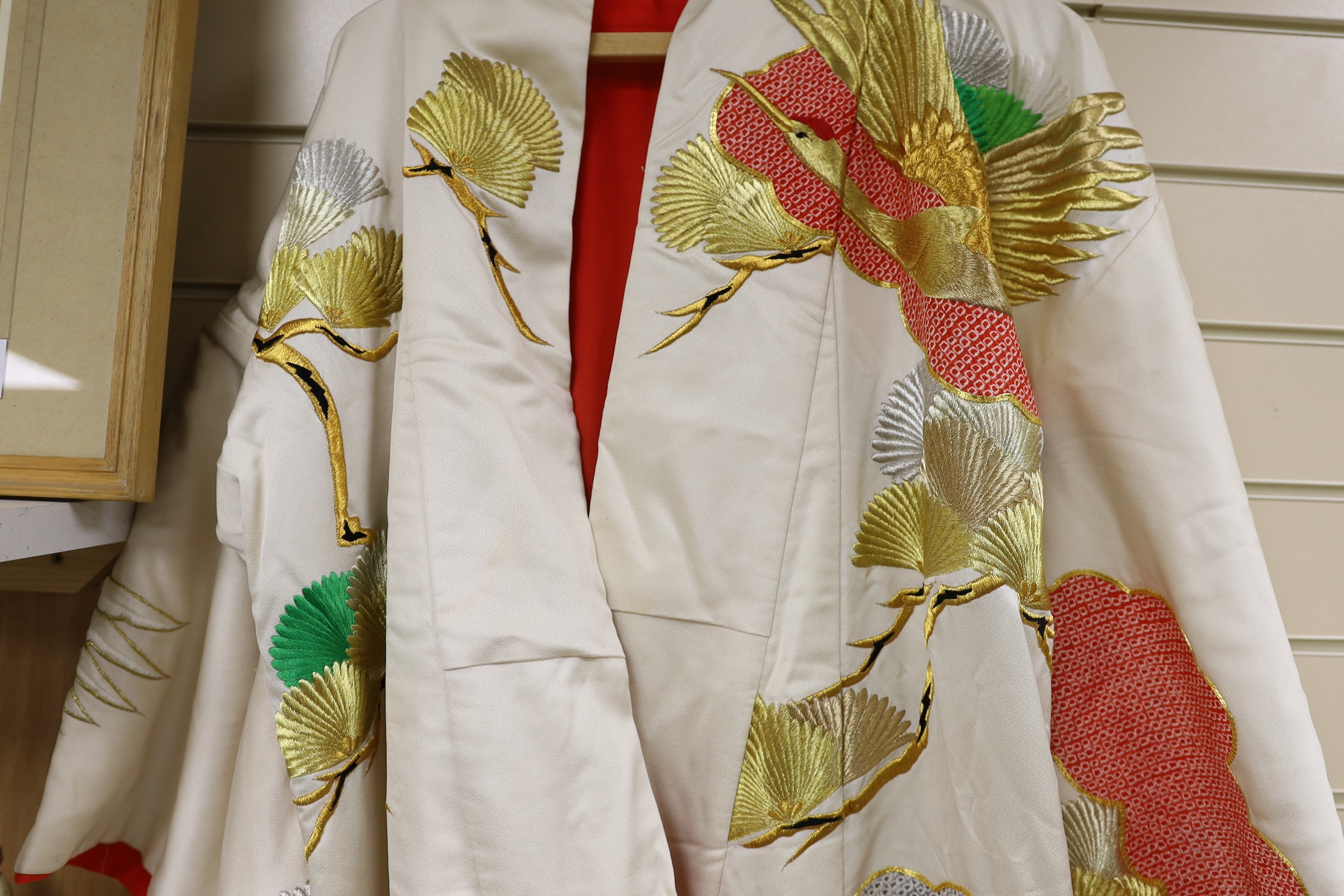 A Japanese cream ground ceremonial kimono, embroidered with coloured silks and metallic embroidery, in an all over design, with flame red silk lining